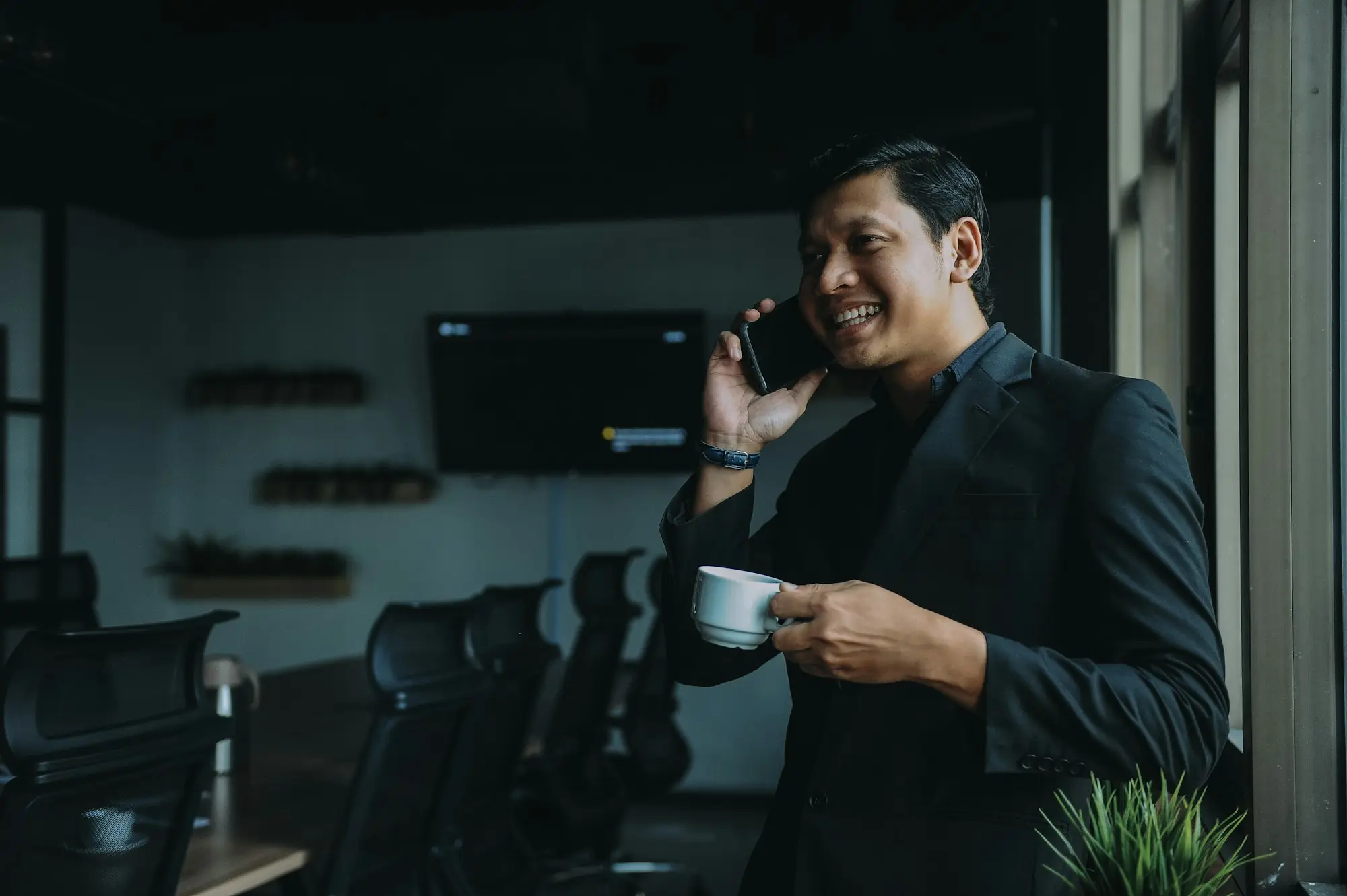 Business owner taking a phone call in the office with a coffee