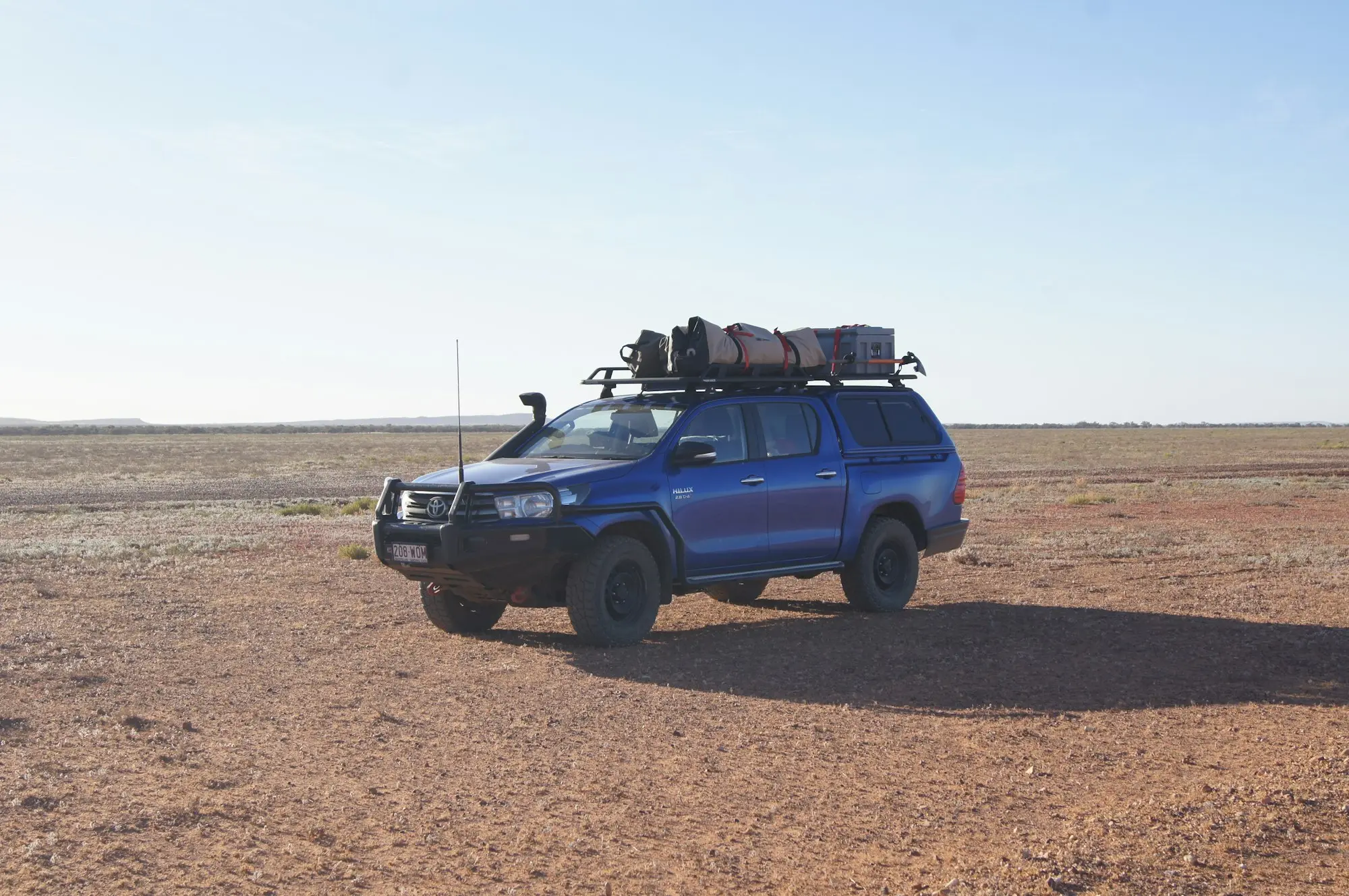 Four-wheel drive ute parked on a red dirt plain in outback Queensland